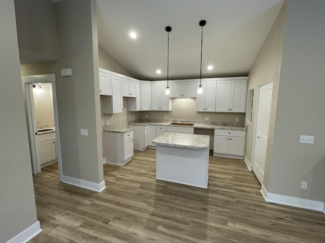 kitchen with white cabinets, a kitchen island, wood finished floors, baseboards, and black electric cooktop