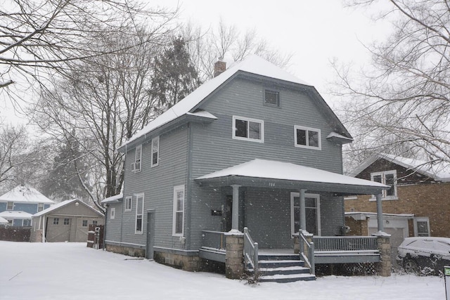 view of front of house featuring covered porch, a garage, and an outbuilding