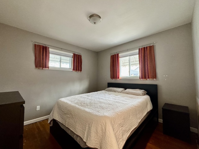 bedroom with dark hardwood / wood-style flooring and multiple windows