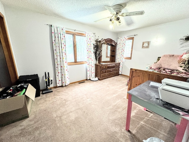 carpeted bedroom with ceiling fan and a textured ceiling