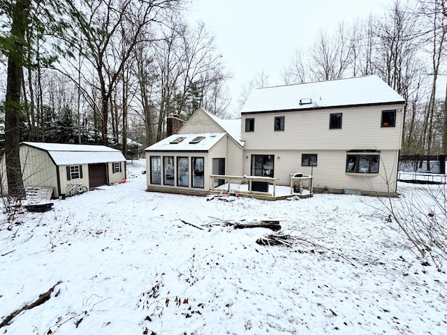 snow covered rear of property featuring an outbuilding and a deck