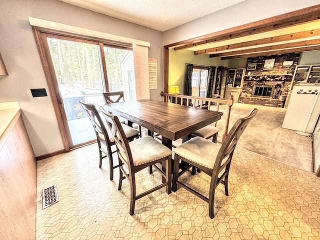 dining room featuring a textured ceiling and a brick fireplace