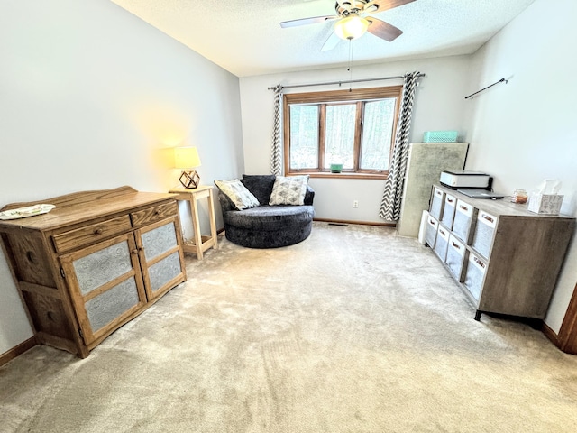 living area featuring a textured ceiling, ceiling fan, and light carpet