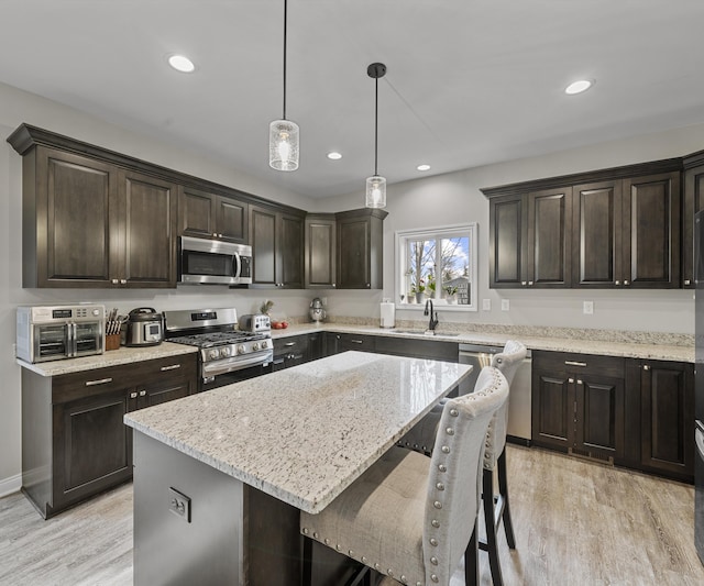 kitchen featuring sink, a center island, dark brown cabinets, hanging light fixtures, and stainless steel appliances