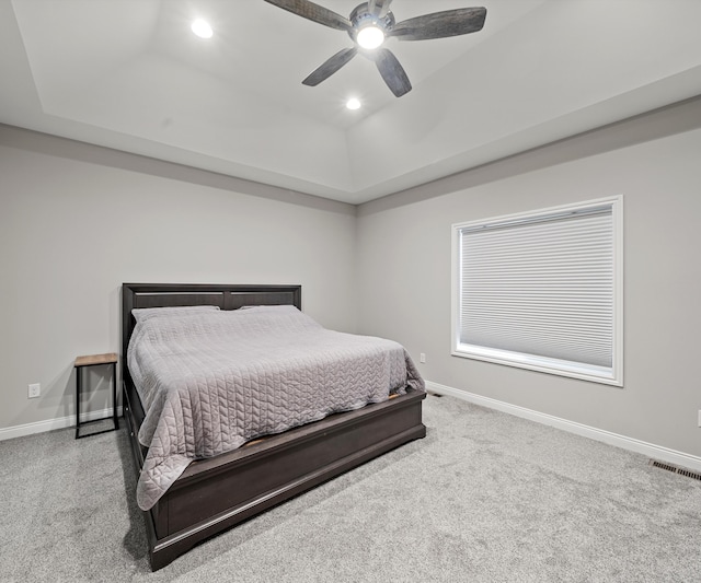 carpeted bedroom featuring a raised ceiling and ceiling fan