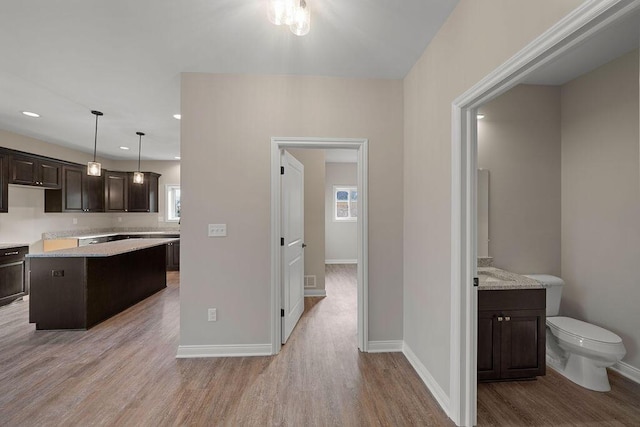 kitchen with a kitchen island, dark brown cabinets, pendant lighting, and light wood-type flooring