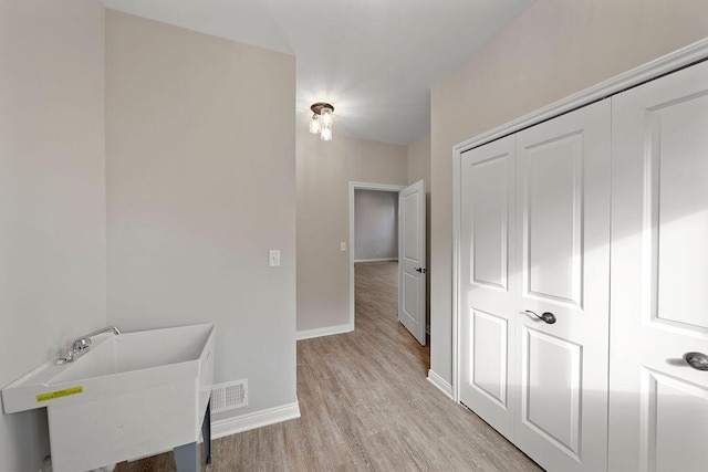 corridor featuring sink and light hardwood / wood-style flooring