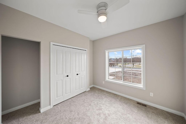 unfurnished bedroom featuring light carpet, a closet, and ceiling fan