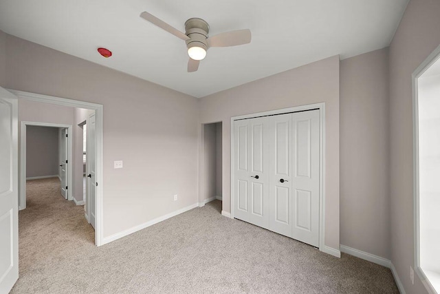 unfurnished bedroom featuring ceiling fan, light colored carpet, and a closet