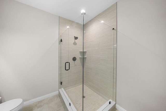 bathroom featuring a shower with door and toilet