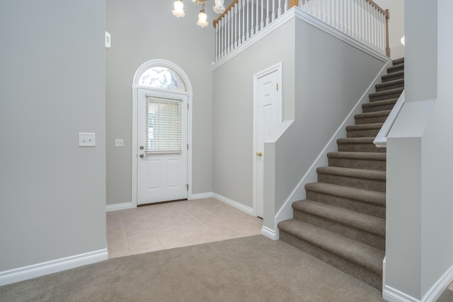 foyer entrance featuring light carpet, a high ceiling, and a chandelier