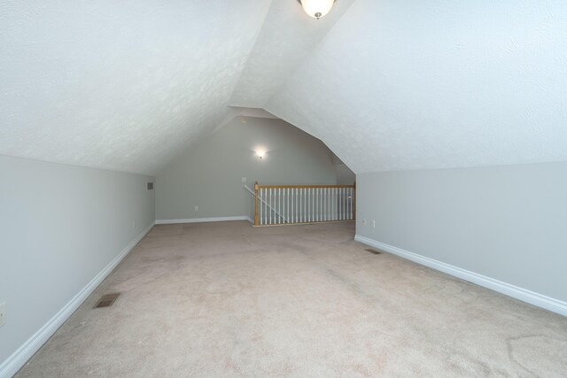 additional living space featuring carpet flooring, a textured ceiling, and vaulted ceiling