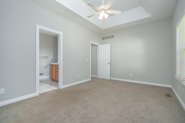 unfurnished bedroom featuring ceiling fan, light carpet, and connected bathroom