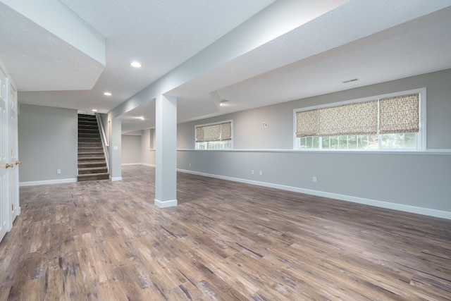 basement featuring hardwood / wood-style floors, a textured ceiling, and a wealth of natural light