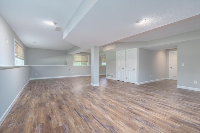 basement with plenty of natural light, wood-type flooring, and a textured ceiling