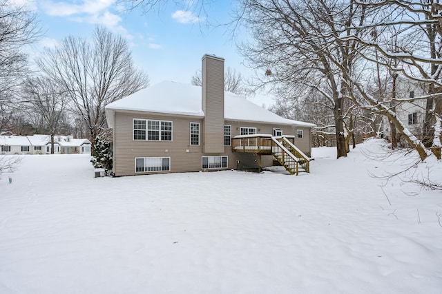 snow covered house featuring a wooden deck