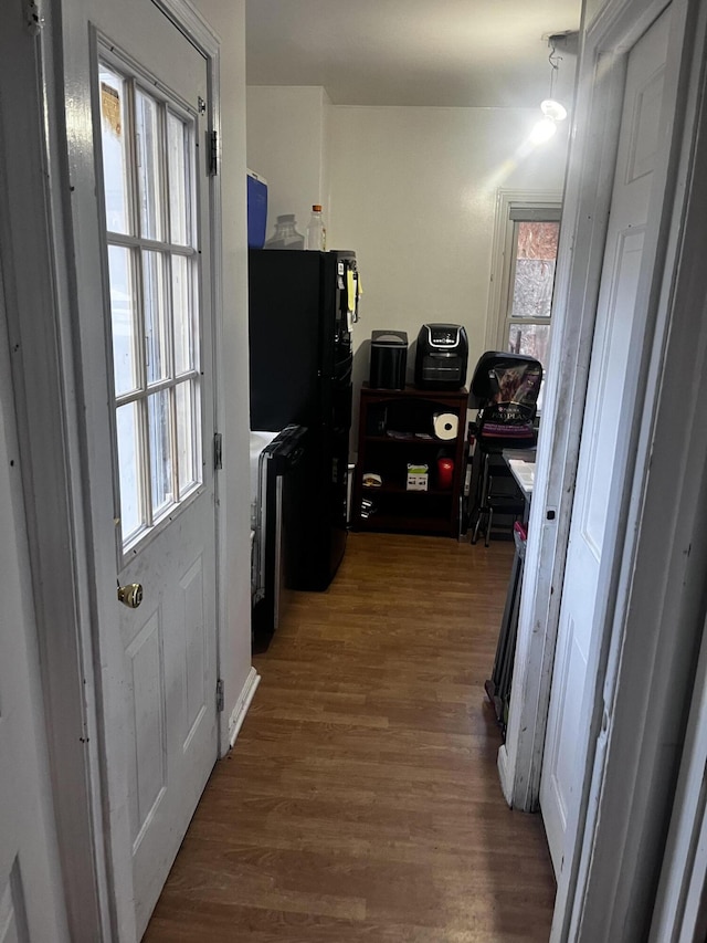 interior space with dark hardwood / wood-style floors, black fridge, and a wealth of natural light