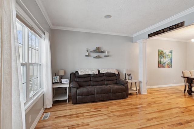 living room featuring ornate columns, crown molding, and light wood-type flooring