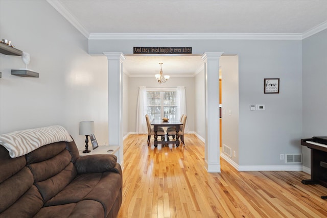 living room with a notable chandelier, light wood-type flooring, crown molding, and ornate columns