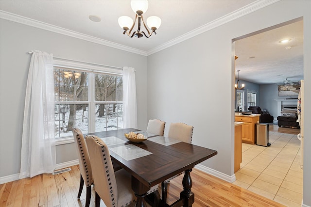 dining area featuring plenty of natural light, light hardwood / wood-style floors, ornamental molding, and a chandelier