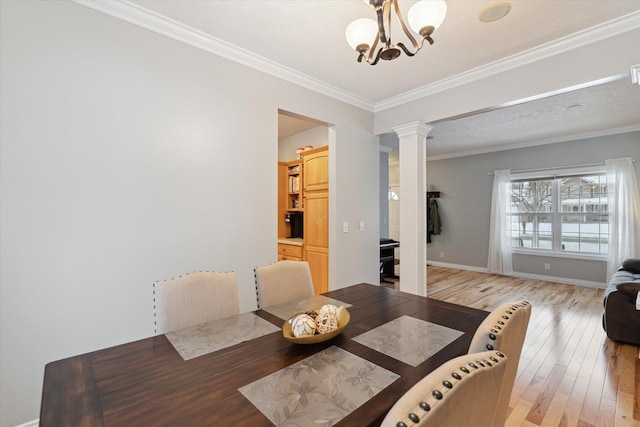 dining room with hardwood / wood-style flooring, ornate columns, crown molding, and a notable chandelier