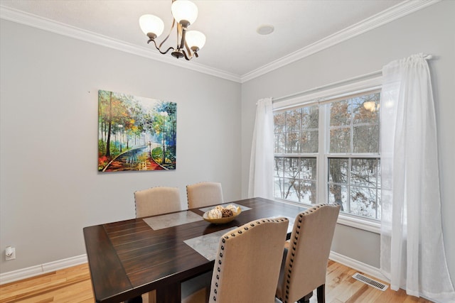 dining room with an inviting chandelier, light hardwood / wood-style flooring, and crown molding