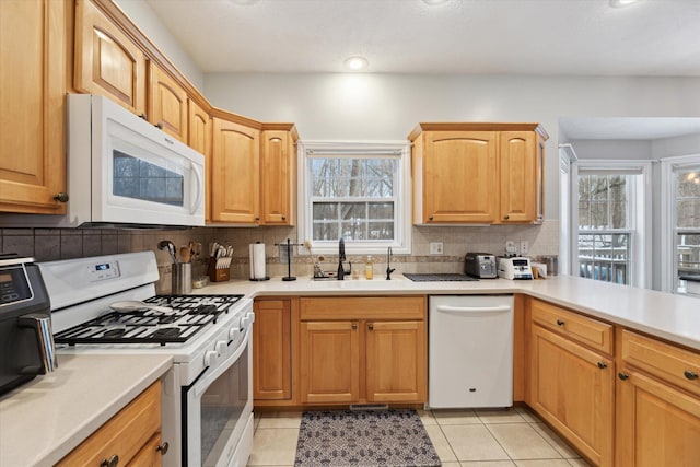 kitchen with light tile patterned flooring, white appliances, backsplash, and sink