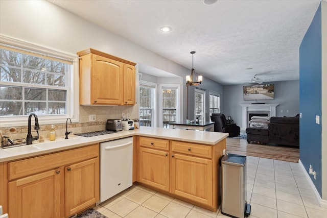 kitchen featuring dishwasher, sink, hanging light fixtures, kitchen peninsula, and light tile patterned floors