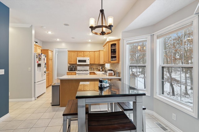 kitchen with a healthy amount of sunlight, white appliances, light tile patterned floors, and an inviting chandelier