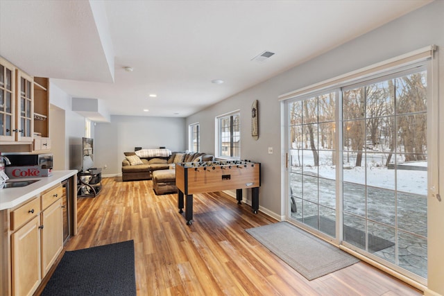 game room featuring light hardwood / wood-style floors, beverage cooler, and sink