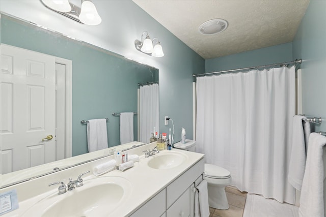 bathroom with tile patterned floors, vanity, a textured ceiling, and toilet