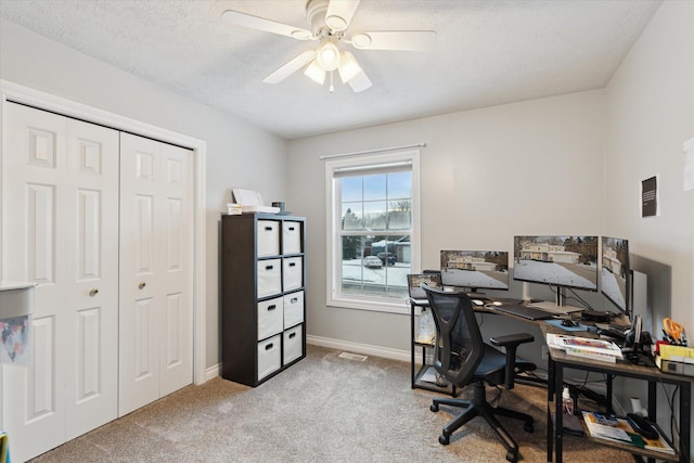 carpeted office with a textured ceiling and ceiling fan