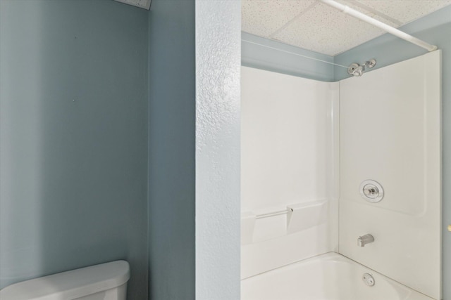 bathroom with bathing tub / shower combination, a paneled ceiling, and toilet