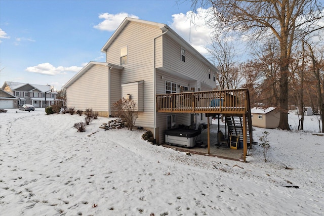 snow covered house featuring a hot tub and a wooden deck