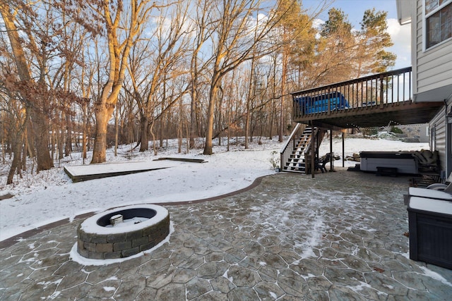 snowy yard featuring a fire pit, a wooden deck, and a hot tub