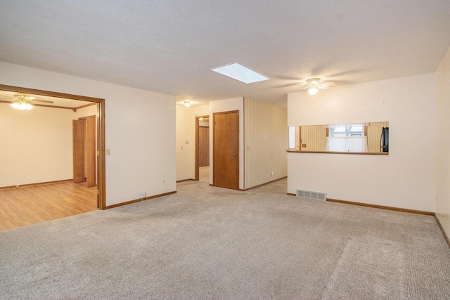 carpeted empty room with ceiling fan and a skylight