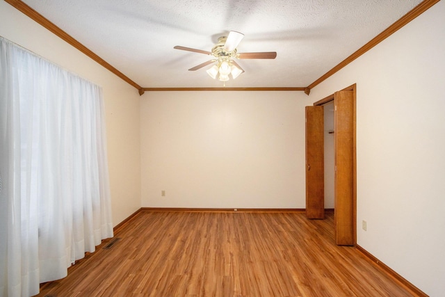 empty room with ceiling fan, ornamental molding, a textured ceiling, and light wood-type flooring