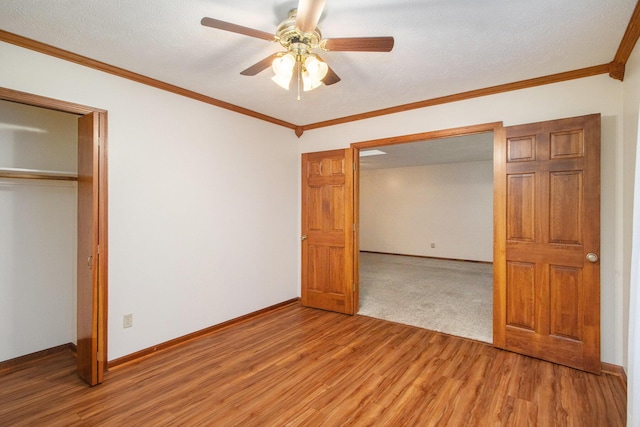 unfurnished bedroom featuring a closet, ceiling fan, crown molding, and hardwood / wood-style floors