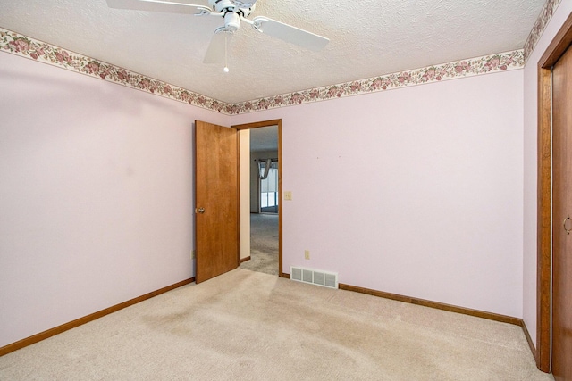 unfurnished bedroom featuring ceiling fan, light colored carpet, and a textured ceiling