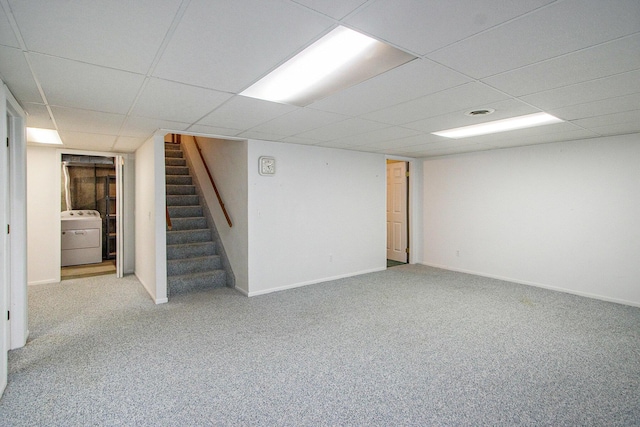 basement featuring a drop ceiling, washer / dryer, and light carpet