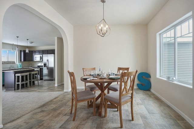 dining room featuring sink, wood-type flooring, and an inviting chandelier