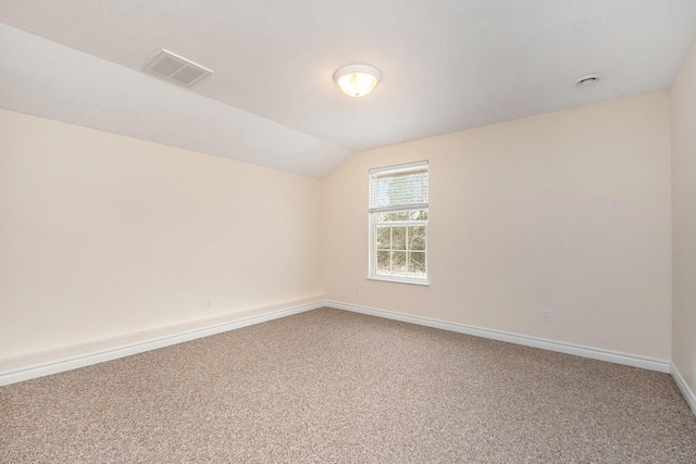 carpeted empty room with vaulted ceiling