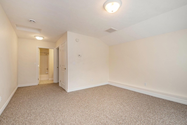 carpeted spare room with vaulted ceiling