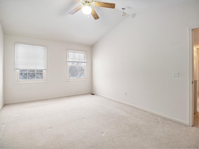 spare room featuring lofted ceiling, light carpet, and ceiling fan