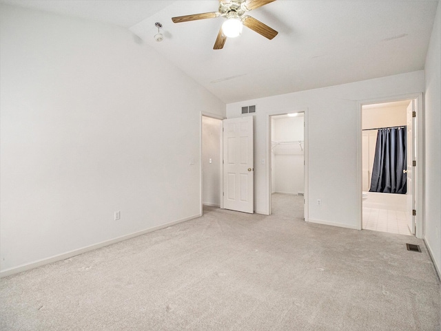 unfurnished bedroom with ensuite bathroom, ceiling fan, a closet, a walk in closet, and light colored carpet