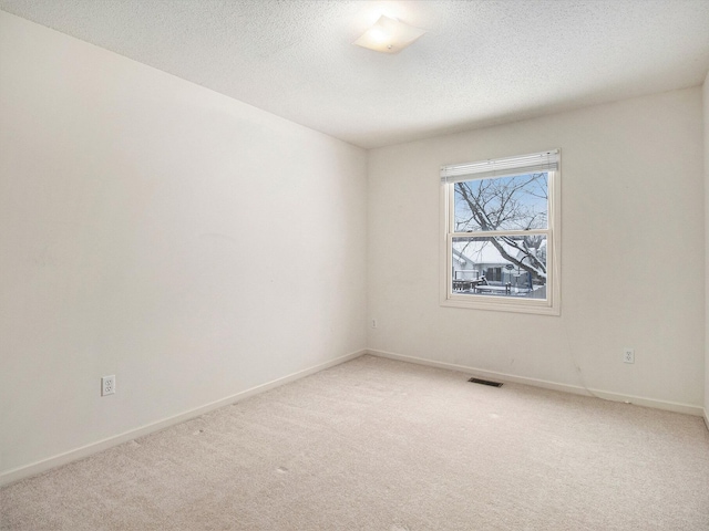 carpeted empty room featuring a textured ceiling