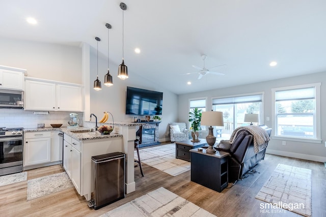 kitchen featuring white cabinetry, sink, stainless steel appliances, pendant lighting, and vaulted ceiling