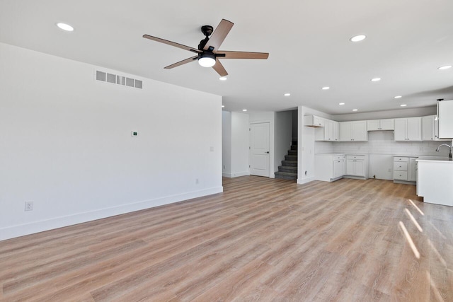 unfurnished living room featuring ceiling fan, sink, and light hardwood / wood-style floors