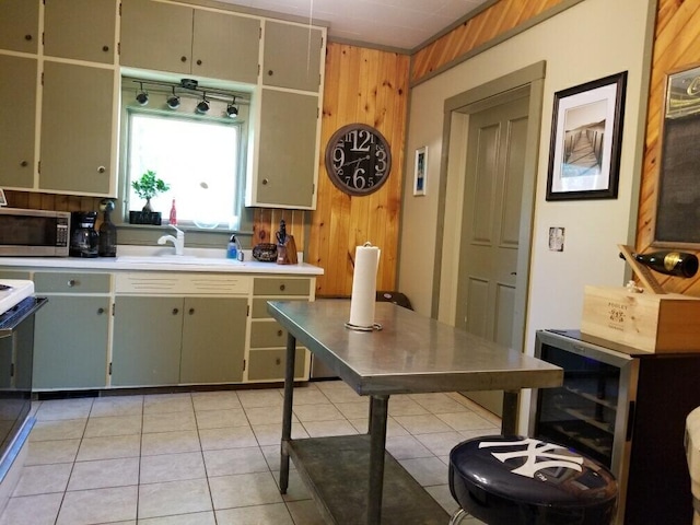 kitchen featuring wood walls, light tile patterned floors, and sink