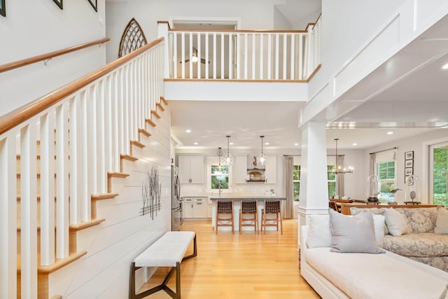 living room with sink, a towering ceiling, light hardwood / wood-style flooring, and a chandelier